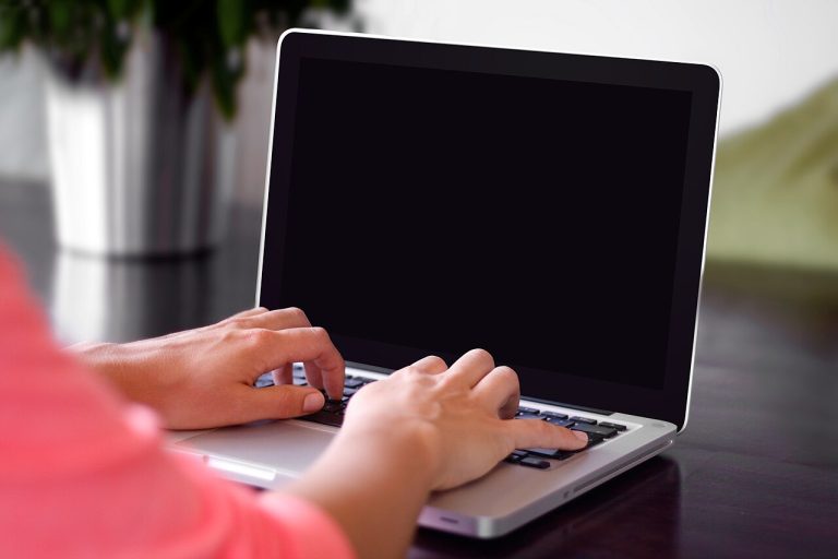 Person typing on a laptop while writing a resume with no experience
