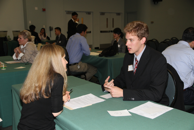A candidate talking with an interviewer at a job interview table