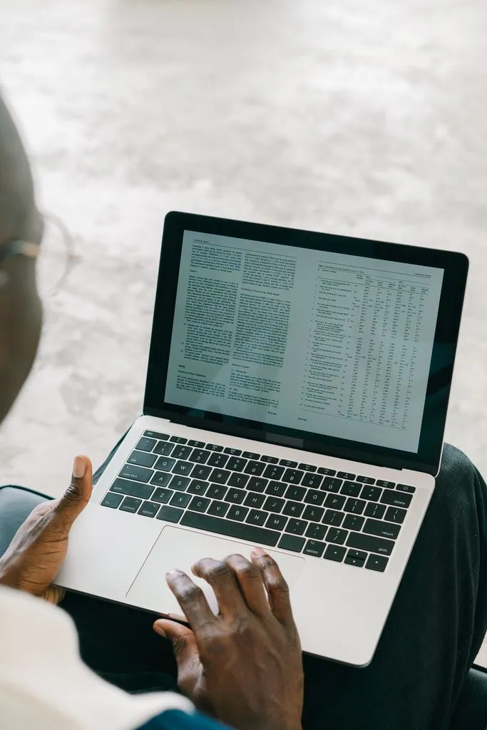 A person reviewing a spreadsheet with rows of data on a laptop screen