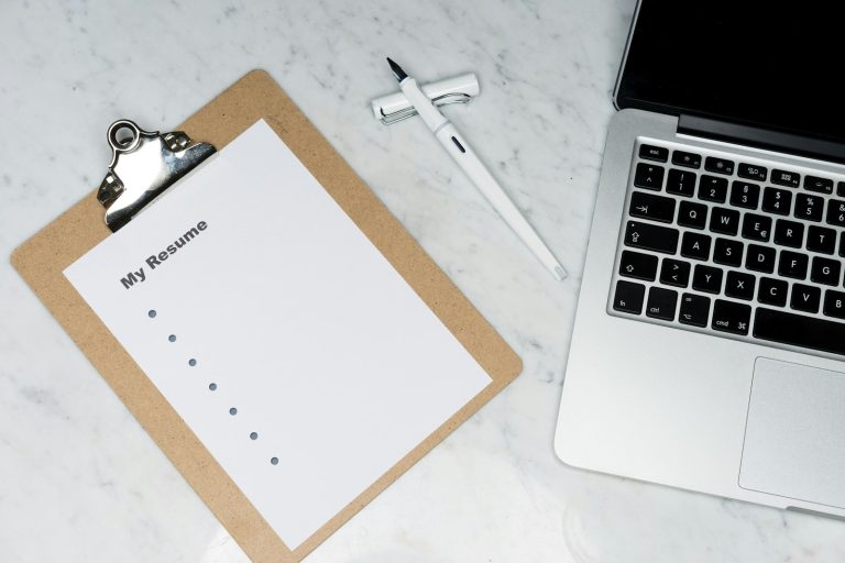 Person writing a resume at a desk while planning how to explain an employment gap on your resume