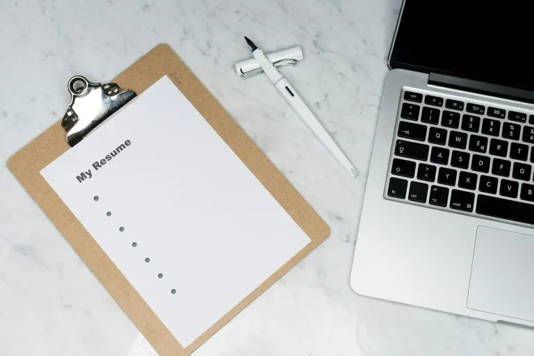 Person writing a resume at a desk while planning how to explain an employment gap on your resume