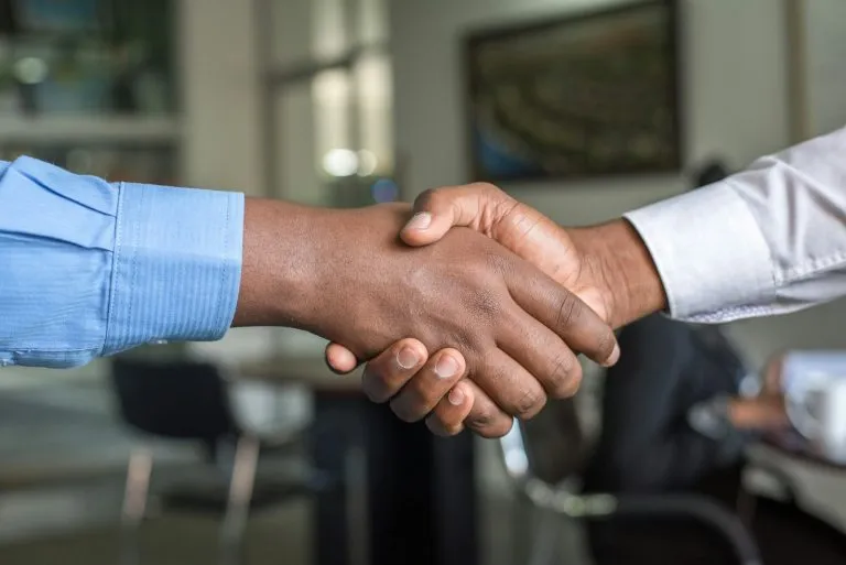 Young graduate shaking hands with an interviewer after answering tell me about yourself for freshers