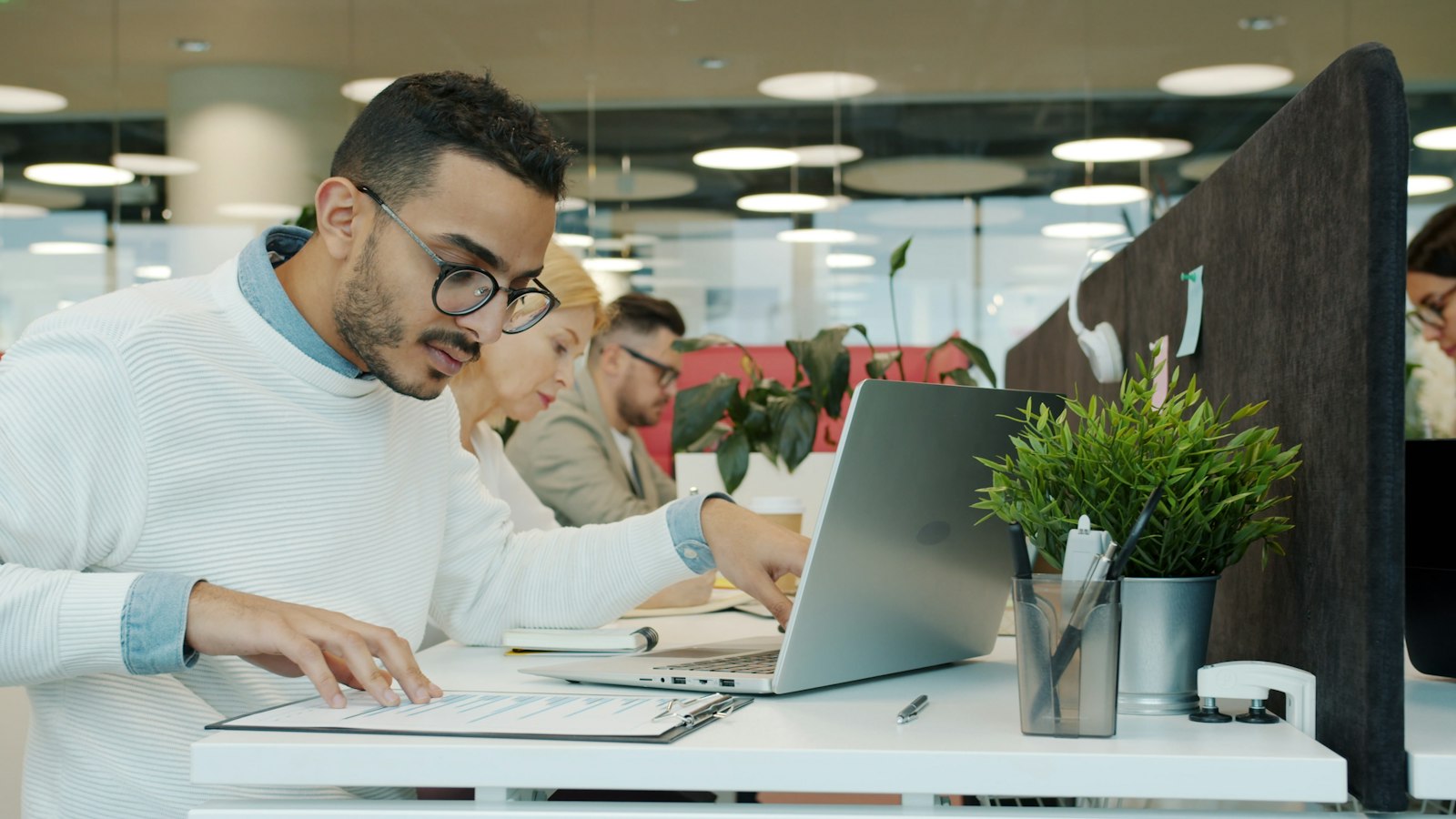 Office worker checking documents at a desk with a laptop
