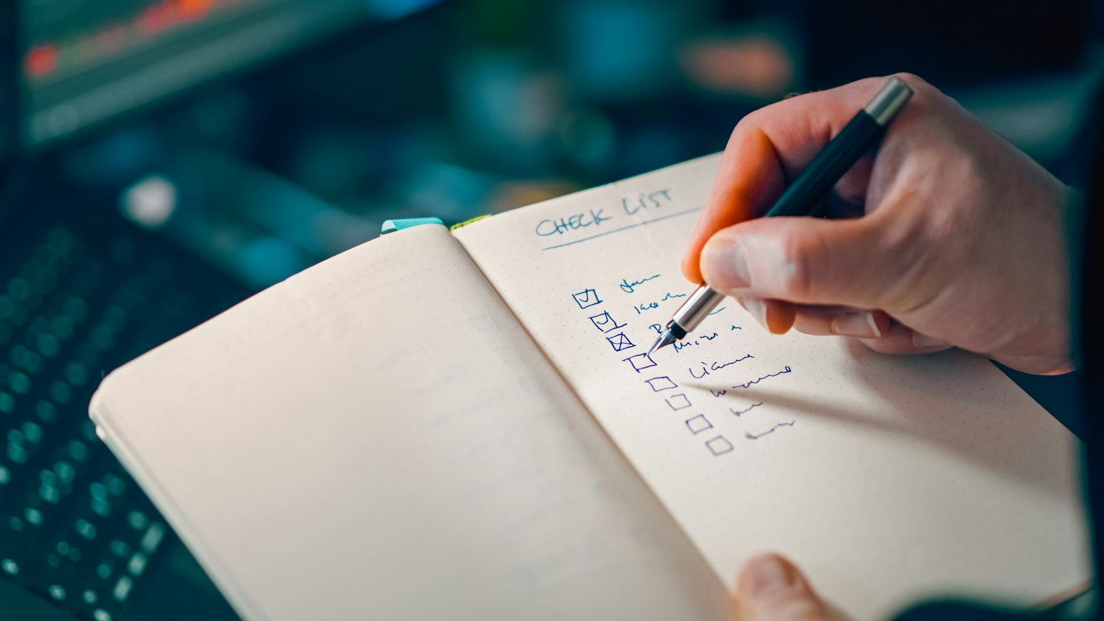 Hand ticking off a handwritten checklist in a notebook