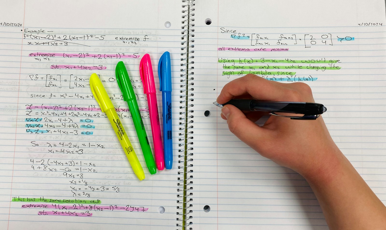 Hand writing study notes in a notebook with colorful highlighters and pens