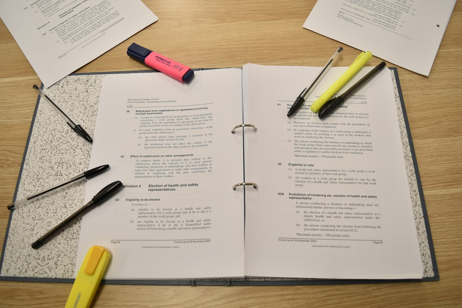 Open study binder with papers, pens and highlighters spread on a desk