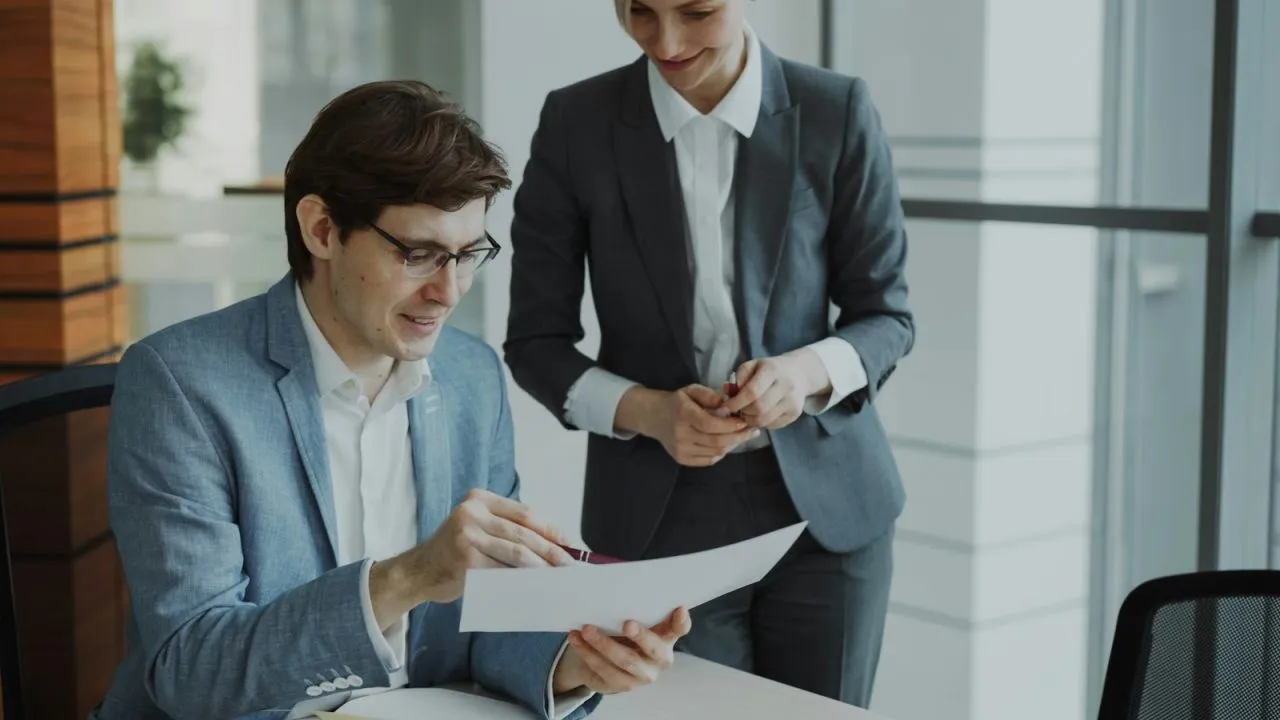 Young intern reviewing a document with his mentor in a bright modern office while learning what is an internship
