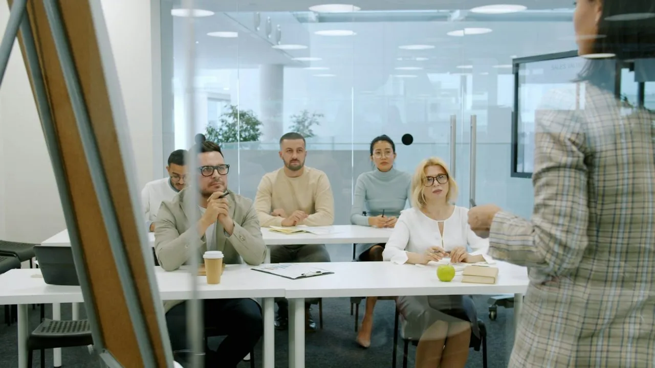 Interns and colleagues listening to a presentation during a team meeting in a modern office