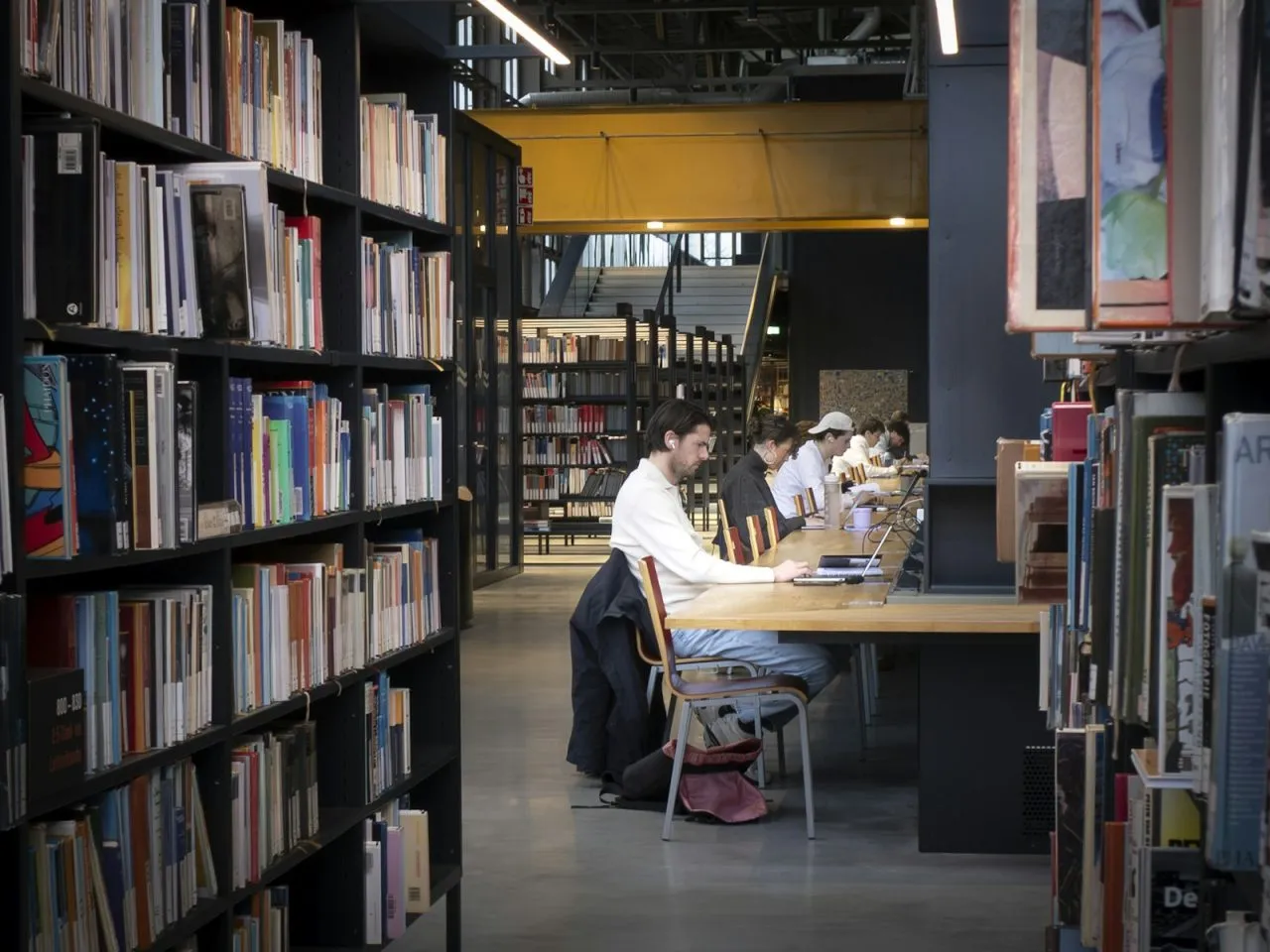 High school students studying together with books and laptops in a bright library while preparing for the national merit scholarship