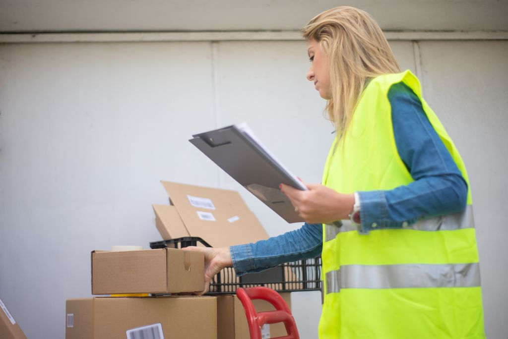 warehouse jobs — a warehouse worker in hi-vis safety gear checking stock